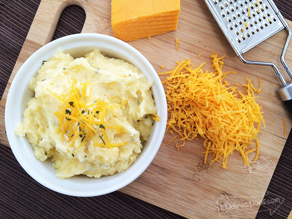 Cheesy Garlic Mashed Potatoes topped with shredded cheddar cheese