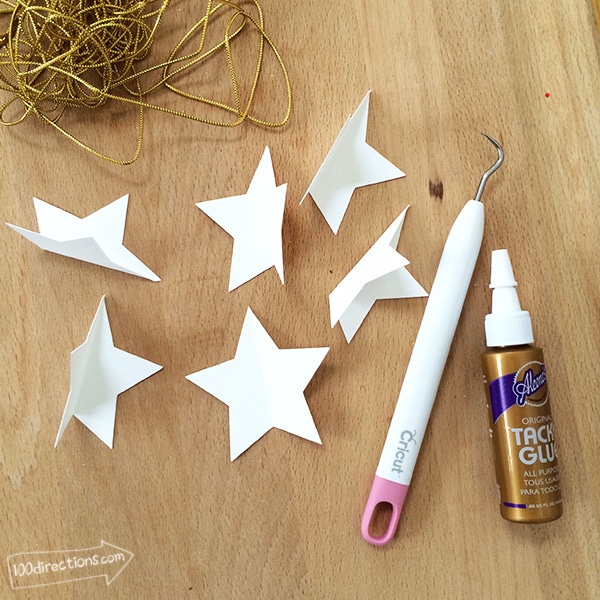 Cut paper stars and other supplies to make a paper star ornament