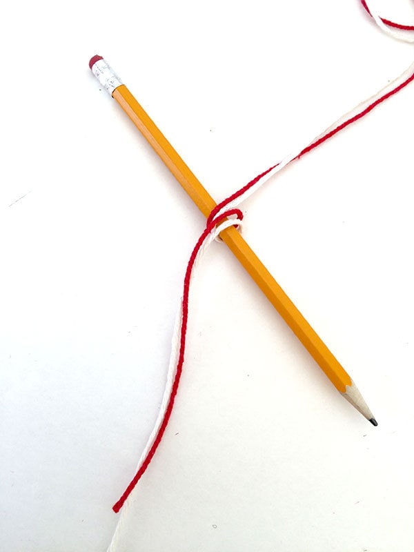 Wrap pencil once with white and red yarn together