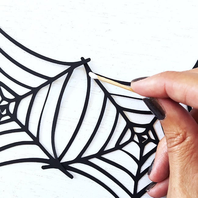 Use a toothpick to apply glue to the spiderweb