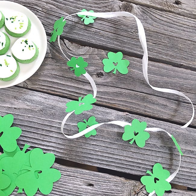 Glue paper shamrocks to raffia to make garland