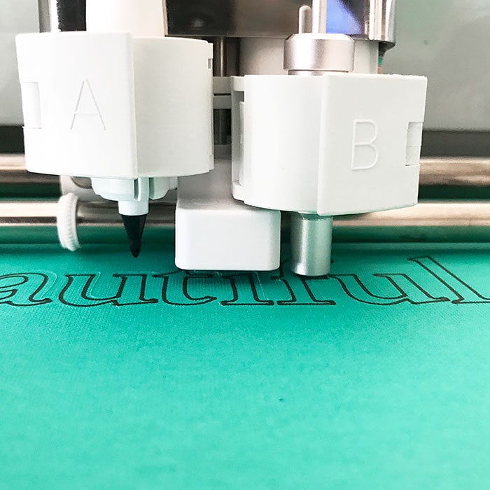 Cricut machine cutting around the word