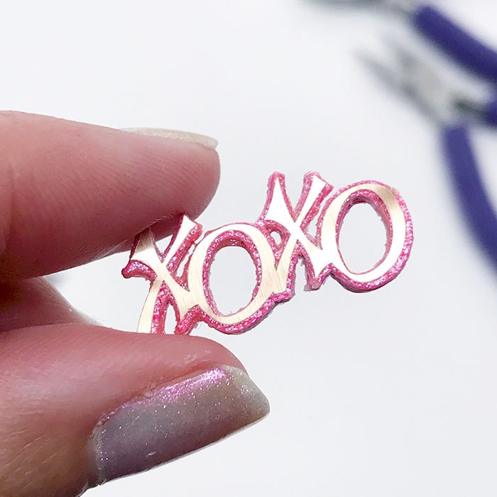 Layer cut pieces to create XOXO charm